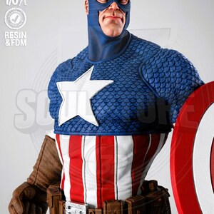 May include: A detailed Captain America figurine. The figure wears a blue and white star-emblazoned costume with a red, white, and blue striped torso. The figure is holding a red shield. The figure is 1/6 scale.