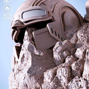 May include: A detailed, brown, futuristic helmet with a visor and intricate design, resting on a rocky surface. The image includes text indicating it is presupported, tested, and made with resin and FDM, at a 1/6 scale.