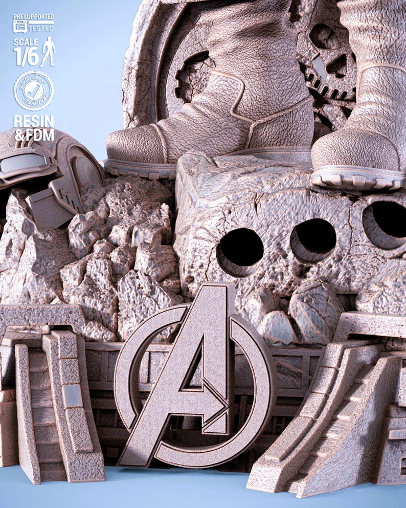 May include: A detailed, light gray statue featuring the Avengers logo, boots, and a helmet. The statue is made of resin and FDM, with a scale of 1/6. The design includes a rocky, textured base and architectural elements.