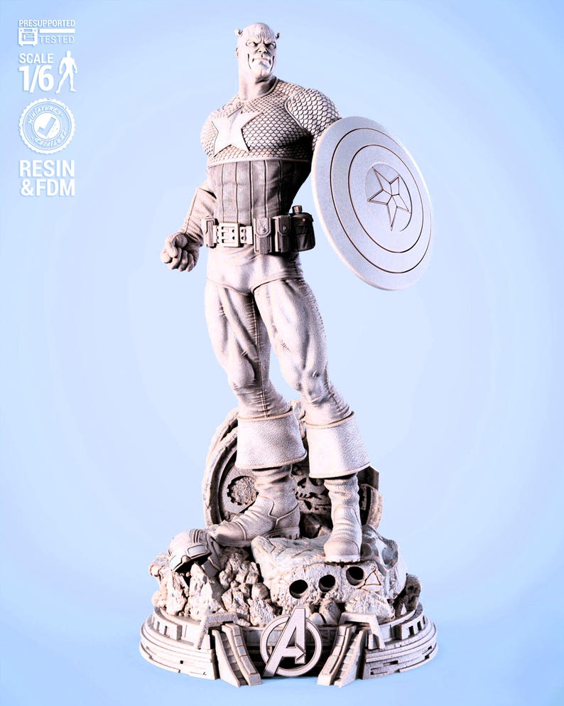 May include: A detailed statue of Captain America in a dynamic pose, holding his shield. The figure is in a light color, standing on a rocky base with the Avengers logo. The statue is labeled "SCALE 1/6" and "RESIN & FDM".
