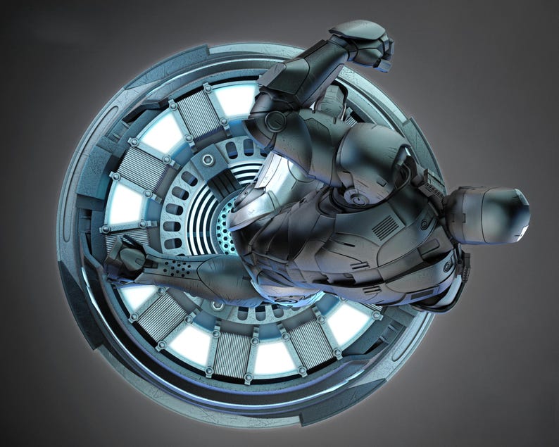 May include: A futuristic, silver-colored armored figure is positioned within a circular, metallic structure. The structure has a radial design with glowing blue lights. The figure is in a dynamic pose, suggesting movement or action, against a gray background.