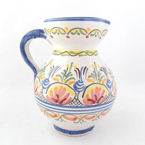 May include: A white ceramic mug with a black handle and the text "But First, Coffee" in a bold, black font. The mug is set against a blurred background, suggesting a cosy setting.