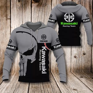 Pode incluir: Moletom cinza e preto Kawasaki Racing Team com um gráfico de caveira na frente. O moletom apresenta o logotipo da Kawasaki, as palavras "Kawasaki Racing Team" e a opção de adicionar um nome. As mangas têm a palavra "Kawasaki".