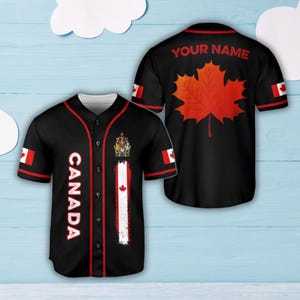 Könnte beinhalten: Schwarzes Baseball-Trikot mit roter Paspelierung und dem Wort "CANADA" in Weiß. Mit kanadischer Flagge und Wappen. Auf der Rückseite des Trikots befindet sich ein großes rotes Ahornblatt und der Text "YOUR NAME".