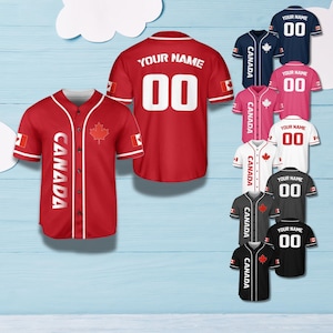 May include: A selection of baseball jerseys in different colours, such as red, navy, pink, white, grey, and black. Each jersey displays the word "CANADA", a maple leaf, and the number "00" or the text "YOUR NAME".