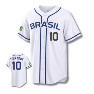 May include: White baseball jersey with "BRASIL" in blue lettering and the number "10" in gold and blue. Features a Brazilian flag patch on the sleeve. A smaller jersey with "YOUR NAME" and the number "10" is also shown.