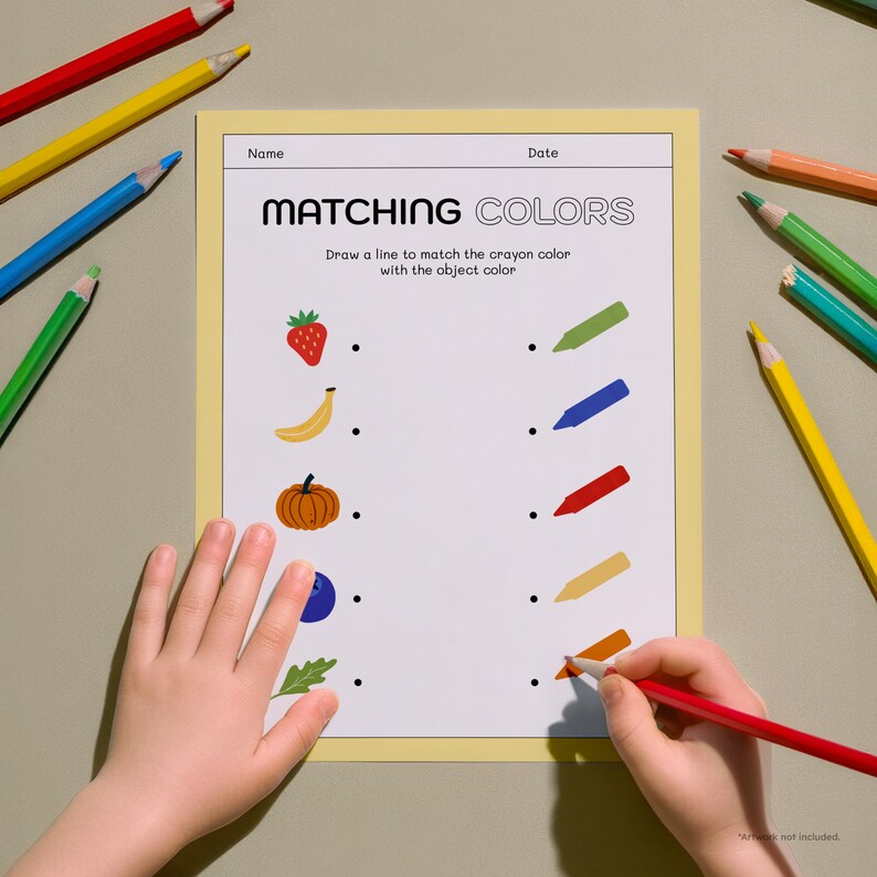 May include: A child's hands are shown working on a "Matching Colors" worksheet. The worksheet features illustrations of a strawberry, banana, pumpkin, blueberry, and leaf. Colored pencils in red, yellow, blue, and green surround the worksheet.