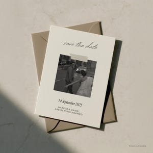 May include: A cream-colored save-the-date card with a black and white photo of a couple. The card includes the text "save the date," the date "14 September 2025," and the names "HARPER & DANIEL ARE GETTING MARRIED." The card is placed on a tan envelope.