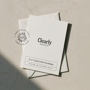 Op de afbeelding: Een witte kaart van 12,7 x 17,8 cm met een envelop, met de tekst "Clearly Mockups". De kaart bevat de tekst "5 x 7 Card with Envelope" en "Intentional Tools for Makers & Artists". Een zon-achtig logo is ook zichtbaar.