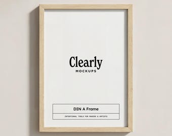 May include: A rectangular, light-colored wooden frame with a white interior. The text "Clearly MOCKUPS" is centered at the top, with "DIN A Frame" and "INTENTIONAL TOOLS FOR MAKERS & ARTISTS" below. The frame is displayed against a neutral background.