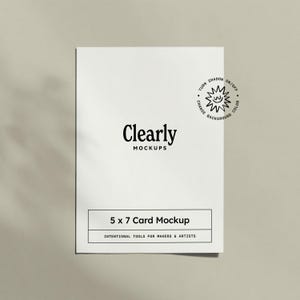 Op de afbeelding: Een witte 5 x 7 kaart mockup met de tekst "Clearly MOCKUPS" in zwart. De kaart bevat ook de tekst "5 x 7 Card Mockup" en "INTENTIONAL TOOLS FOR MAKERS & ARTISTS". Een kleine zonnegrafiek staat in de rechterbovenhoek.