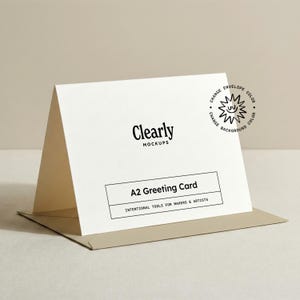 May include: A white A2 greeting card with the text "Clearly MOCKUPS" and "A2 Greeting Card". The card is displayed in a tan envelope. The card also has a graphic with the text "CHANGE ENVELOPE COLOR CHANGE BACKGROUND COLOR".