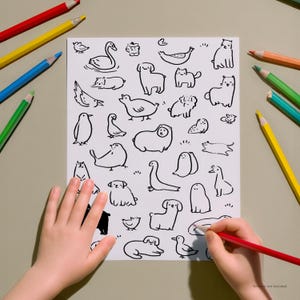 May include: A white paper with black line drawings of various animals, including dogs, cats, and birds. A child's hand is coloring with a red pencil. Colored pencils in red, yellow, blue, and green are scattered around the paper.