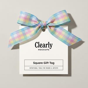 Könnte beinhalten: Ein weißes quadratisches Geschenkanhänger mit einer pastellfarbenen karierten Schleife. Auf dem Anhänger steht "Clearly Mockups" und "Square Gift Tag". Der untere Teil des Anhängers lautet "Intentional Tools for Makers & Artists".