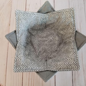 K&ouml;nnte beinhalten: Eine graue Stoffsch&uuml;ssel mit einem wei&szlig;en Zickzackmuster. Die Sch&uuml;ssel ist zusammengefaltet und bereit zum Gebrauch.