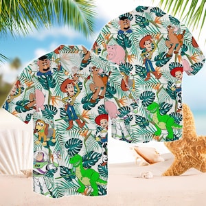 May include: White short-sleeved button-down shirt featuring a tropical pattern with cartoon characters. The design includes Woody, Buzz Lightyear, Rex, and other characters from the Toy Story franchise, set against a backdrop of green leaves.