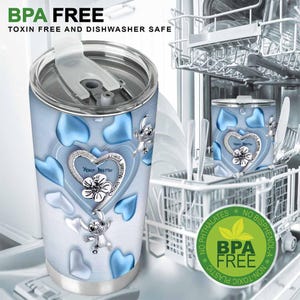 May include: A stainless steel tumbler with a light blue background and blue heart shapes. The tumbler features a heart-shaped design with the text "Your Name" and a cartoon character. The tumbler is BPA free and dishwasher safe.
