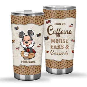 May include: A stainless steel tumbler featuring a cartoon Mickey Mouse design. The tumbler has a coffee bean border and the text "I run on Caffeine Mouse Ears & Cuss Words". The design includes musical notes and coffee cups.