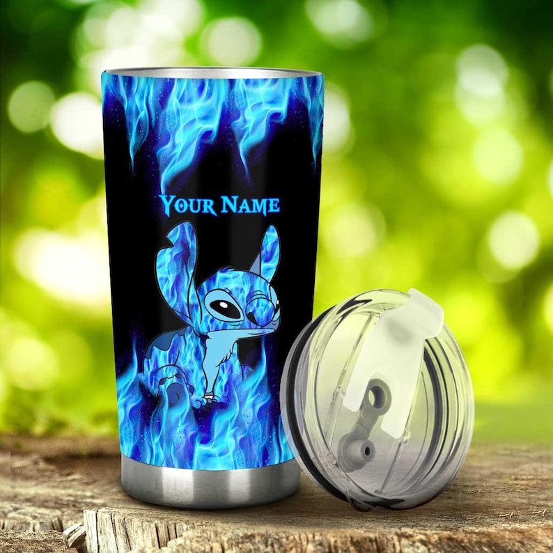 May include: A stainless steel tumbler with a black background and a blue flame design. The tumbler features a cartoon character and the text "YOUR NAME" in blue. A clear lid sits next to the tumbler.