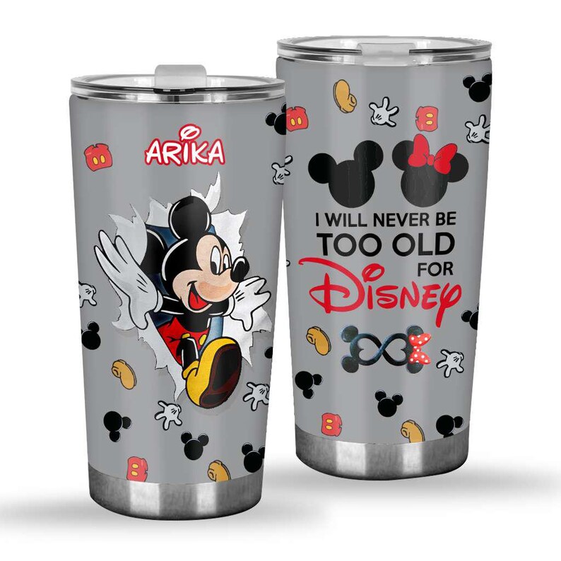 May include: Two stainless steel travel mugs with a grey background and a Disney theme. One mug features Mickey Mouse bursting through a torn paper effect, with the name "Arika". The other mug has the text "I WILL NEVER BE TOO OLD FOR Disney".