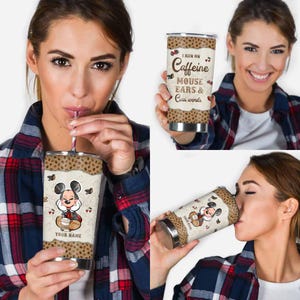 May include: Stainless steel tumbler featuring a cartoon mouse character with a coffee cup. The tumbler has a leopard print pattern and the text "I run on Caffeine, Mouse Ears & Cuss words". The tumbler is held by a person.