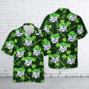 May include: Green and white button-up shirt with a St. Patrick's Day theme. The shirt features a repeating pattern of white trucks, shamrocks, and the phrases "Good Luck" and "Patrick's Day" on a dark green plaid background.