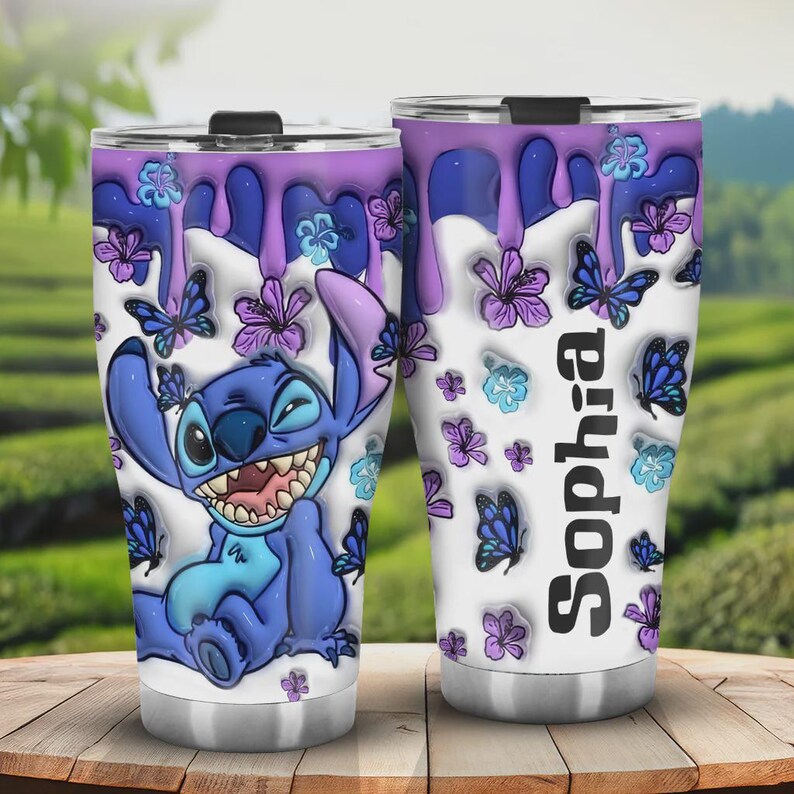 May include: Two stainless steel tumblers with a cartoon Stitch design. The tumblers feature a white background with purple dripping paint, butterflies, and flowers. One tumbler has the name "Sophia" printed vertically.