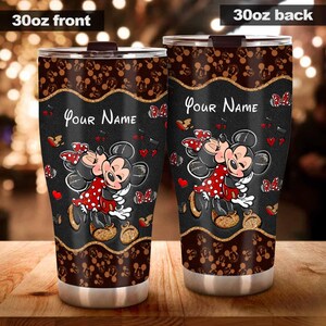 Puede incluir: Dos vasos de acero inoxidable de 887 ml con un fondo negro con Mickey y Minnie Mouse. El dise&ntilde;o incluye corazones rojos, mariposas y el texto "Your Name". Los bordes superior e inferior tienen un patr&oacute;n marr&oacute;n.