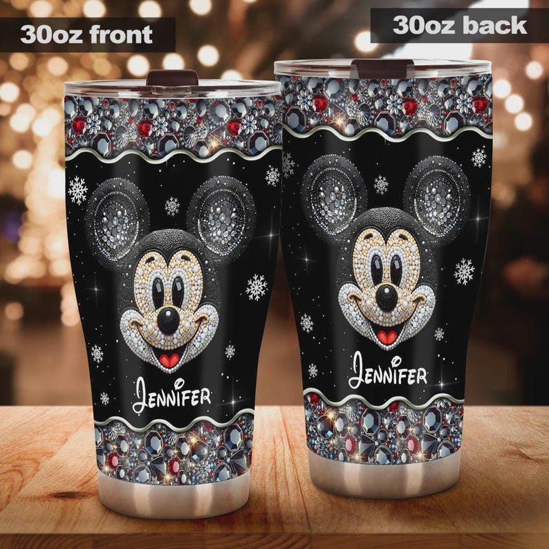 May include: A black 30oz tumbler featuring a Mickey Mouse design with sparkling embellishments. The design includes a smiling Mickey face, snowflakes, and the name "Jennifer". The top and bottom of the tumbler are decorated with jewels.
