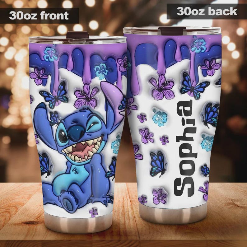 May include: A 30oz stainless steel tumbler featuring a cartoon character, Stitch, winking with a large grin. The design includes purple drips, butterflies, and flowers on a white background. The back of the tumbler has the name "Sophia" in vertical text.