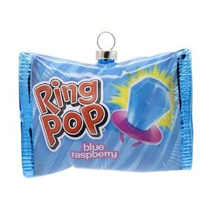 May include: A blue raspberry Ring Pop candy ornament featuring a rectangular wrapper design with the Ring Pop logo in red and white text, a blue gem graphic, and a silver metal hanging loop attached to the top center of the rectangular shape.