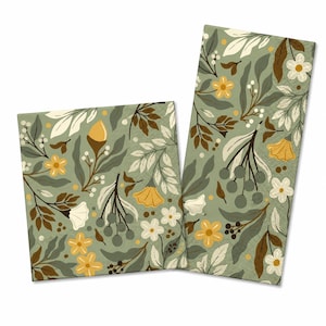 May include: Two paper napkins featuring a botanical pattern on a sage green background. The design includes white and yellow flowers, dark brown leaves, and clusters of small grey berries, creating a repeating floral motif across the surface.