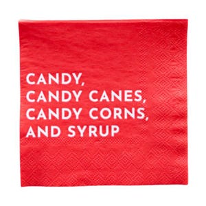 May include: A square red napkin with the words "CANDY, CANDY CANES, CANDY CORNS, AND SYRUP" printed in white. The napkin has a textured surface and is likely made of paper.
