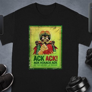 May include: Black t-shirt featuring a retro-style graphic of a Martian with the text "ACK ACK!" in green and yellow. The Martian is depicted with a large head and is pointing. The shirt is surrounded by fitness equipment and accessories.