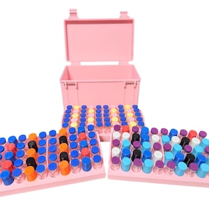 May include: A pink plastic storage case with an open lid, filled with numerous small glass vials. The vials have colorful caps in shades of blue, orange, black, and purple, arranged on pink trays.