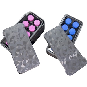 May include: Two rectangular dark gray storage cases with geometric faceted lids. One case contains small glass vials with pink caps, and the other case contains small glass vials with blue caps. The cases are open, revealing the vials inside.