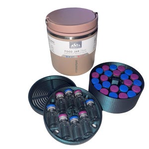 May include: A dusty rose Hydrapeak 25oz food jar with a handle, accompanied by two dark circular 3D-printed organizers. One organizer holds eight clear glass vials with blue and pink caps, while the other contains a grid of twenty-four similar vials.
