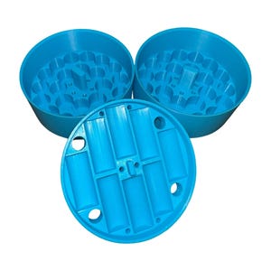 May include: Three bright blue, 3D-printed herb grinders. Two are open, showing the grinding teeth, and one is a lid with rectangular slots and circular holes. The grinders are made of plastic.