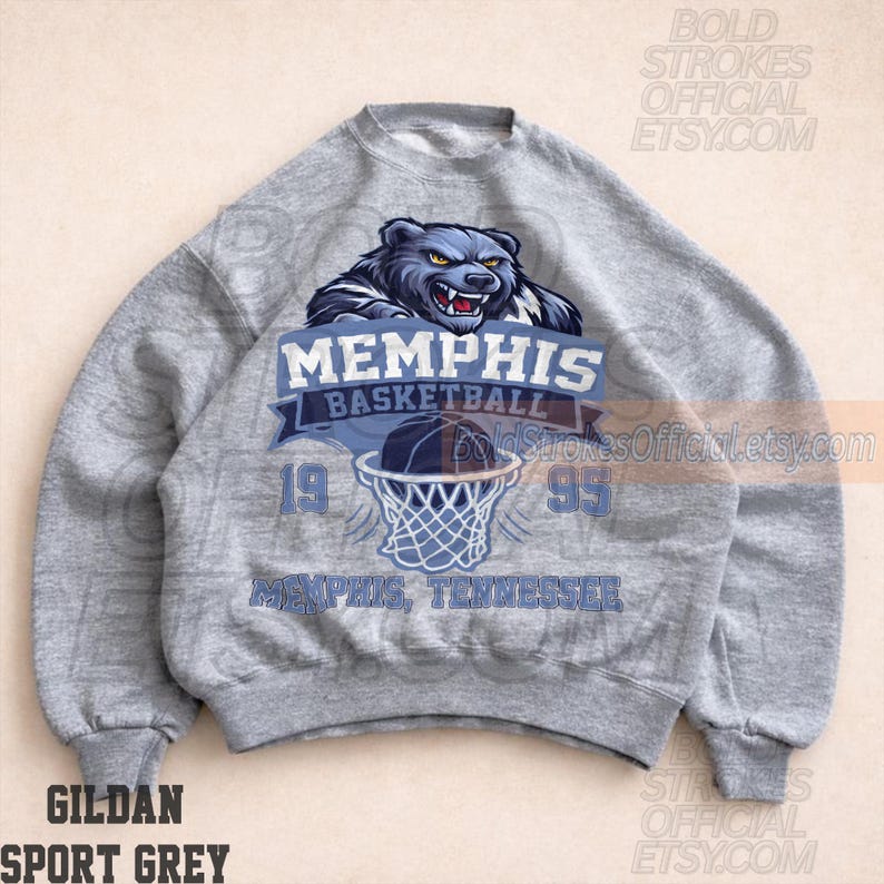 May include: A gray Gildan Sport Grey sweatshirt featuring a Memphis Basketball design. The design includes a blue bear graphic above the text "MEMPHIS BASKETBALL" and a basketball going into a net. The year "1995" is also displayed.