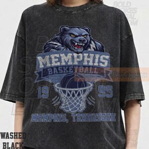 May include: Washed black t-shirt featuring a Memphis basketball design. The design includes a bear graphic, the words "MEMPHIS BASKETBALL", a basketball going into a net, and the numbers "19" and "95". The text "MEMPHIS, TENNESSEE" is also included.