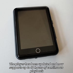 Puede incluir: Un reproductor multimedia digital negro con una pantalla rectangular y un borde negro. El dispositivo tiene un botón circular en la parte inferior de la pantalla. El texto dice que el reproductor admite hasta 10 horas de reproducción continua y mide 6 cm x 8 cm.