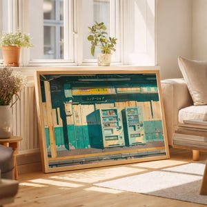 Könnte beinhalten: Gerahmter Druck mit einer japanischen Bahnhofsszene mit Verkaufsautomaten. Das Kunstwerk hat eine Vintage-Ästhetik mit Türkis- und Gelbtönen. Der Rahmen besteht aus hellem Holz. Der Druck wird in einem gut beleuchteten Raum ausgestellt.