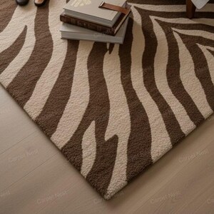 May include: A rectangular rug featuring a zebra stripe design in brown and cream. The rug has a textured surface and is placed on a light-coloured wooden floor. Books are stacked on the rug.