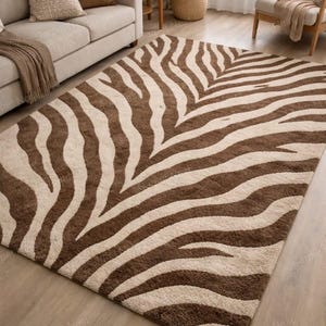 May include: A rectangular rug featuring a zebra stripe design in brown and beige. The rug's pattern consists of curved stripes, and it is placed on a wooden floor. The rug is a decorative item.