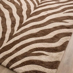 May include: A rectangular rug with a zebra stripe design in brown and beige. The rug has a soft, textured appearance, suitable for a living room or bedroom. The design features wide, irregular stripes.
