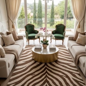 May include: A living room featuring a zebra-patterned rug, two beige sofas, and two green armchairs. A gold coffee table with books and a plant is in the centre. Large windows offer a view of trees and a chandelier hangs from the ceiling.
