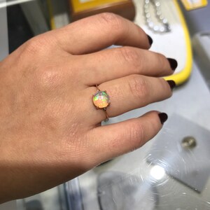 May include: A rose gold ring with a round, multi-colored opal gemstone.