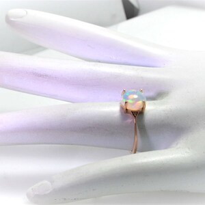 May include: A delicate ring with a white opal gemstone set in a rose gold band.
