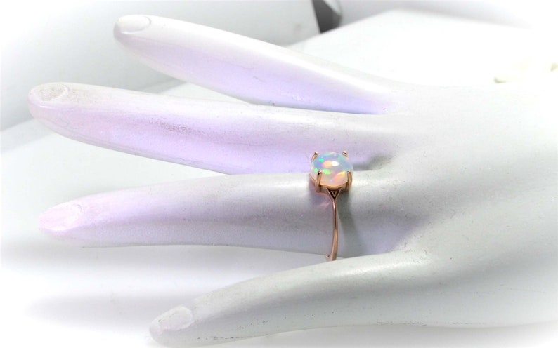May include: A delicate ring with a white opal gemstone set in a rose gold band.