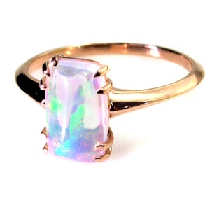 May include: A rose gold ring with a rectangular iridescent opal gemstone.